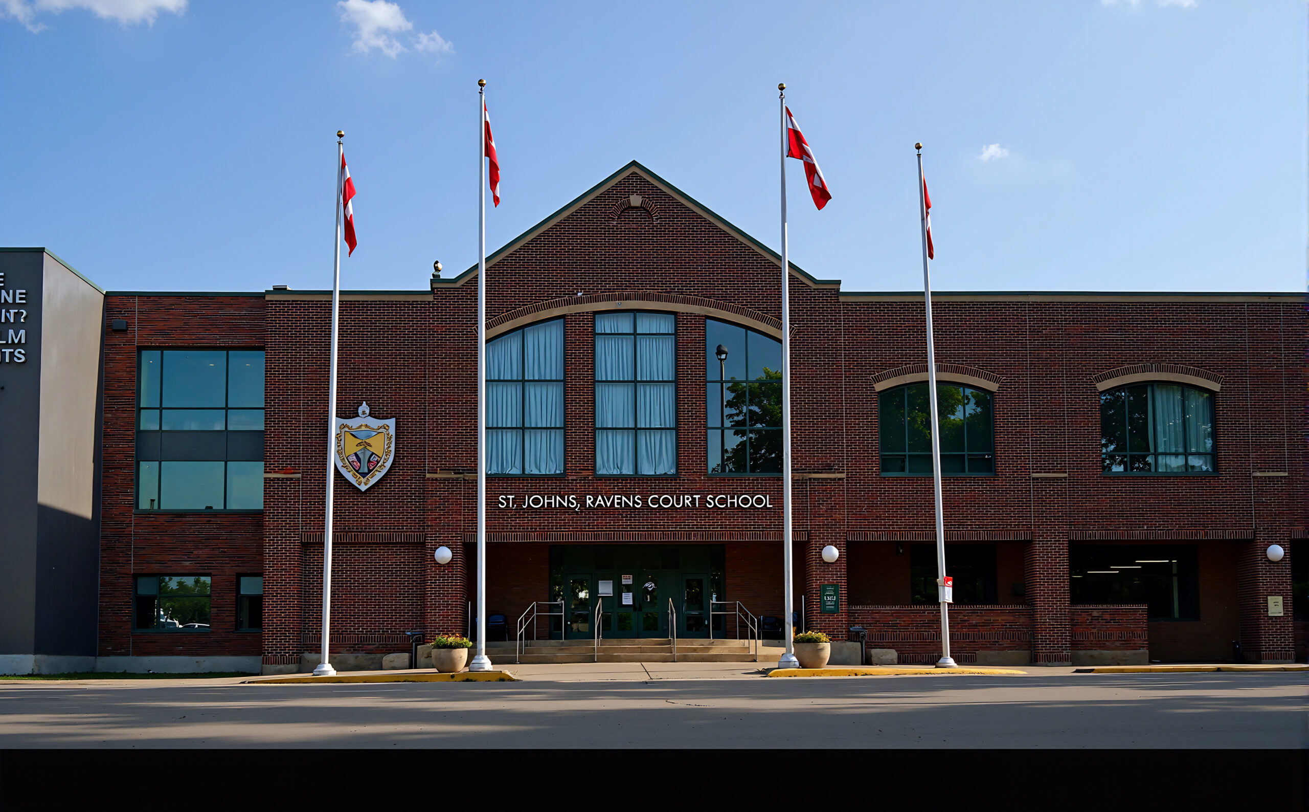 Front view of St. John's-Ravenscourt School in Winnipeg with Canadian flags and red brick architecture
